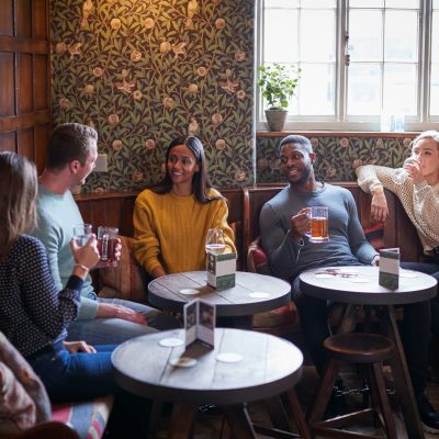 Group Of Friends Meeting For Lunchtime Drinks In Traditional English Pub